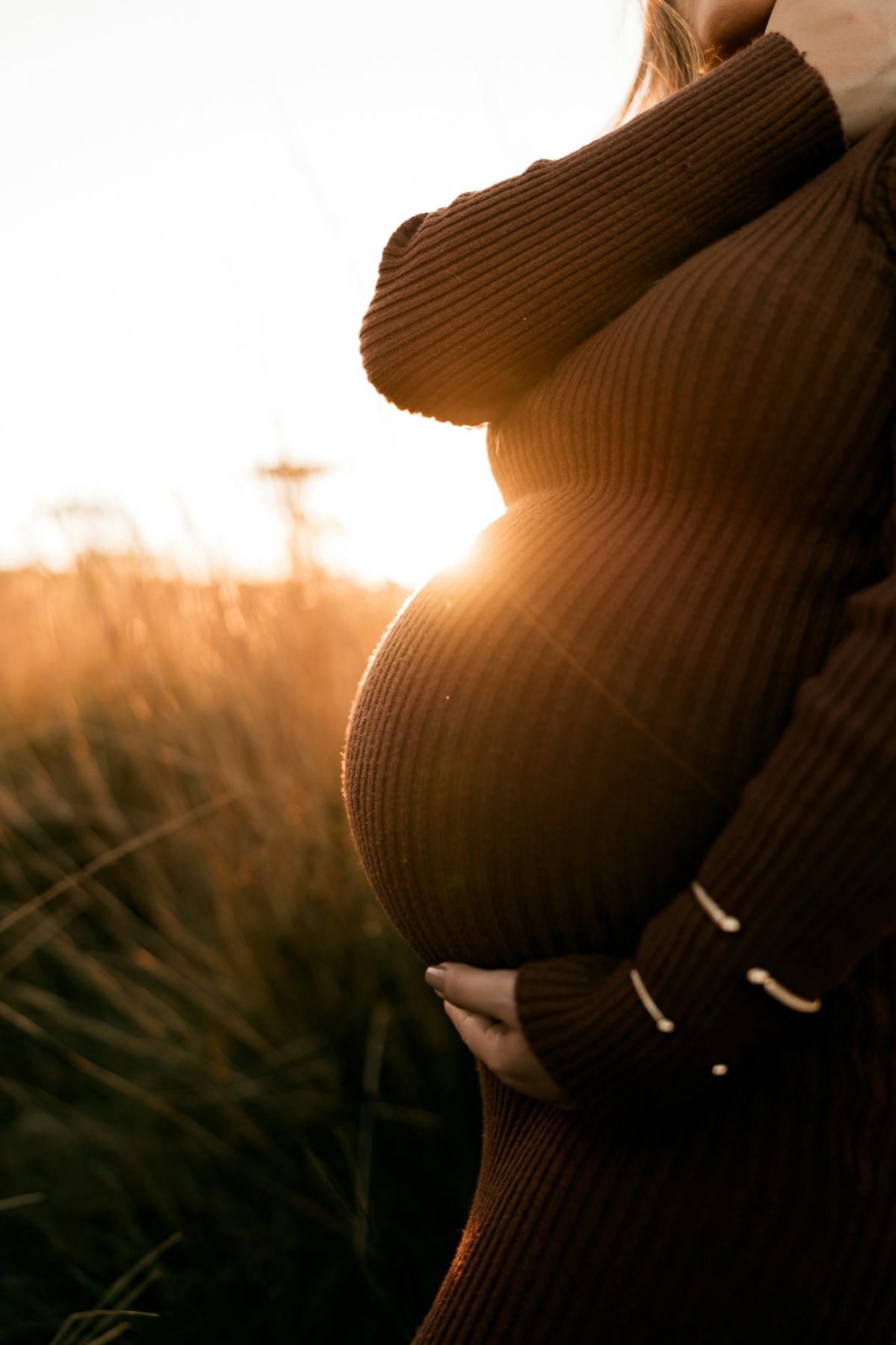 An expecting mother cradling her belly in golden evening light