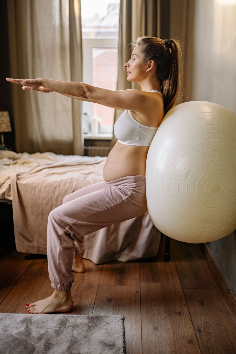 A woman doing a wall squat against an exercise ball